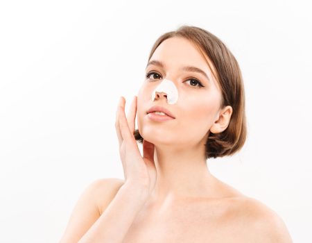 Beauty portrait of a sensual shirtless woman with short brunette hair wearing cosmetic patch on her face isolated over white background